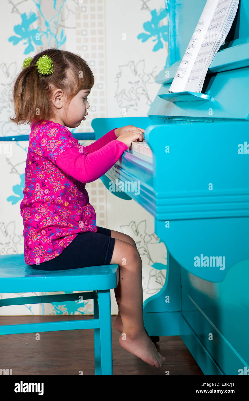 Kleines Mädchen spielt das blaue Klavier Stockfoto