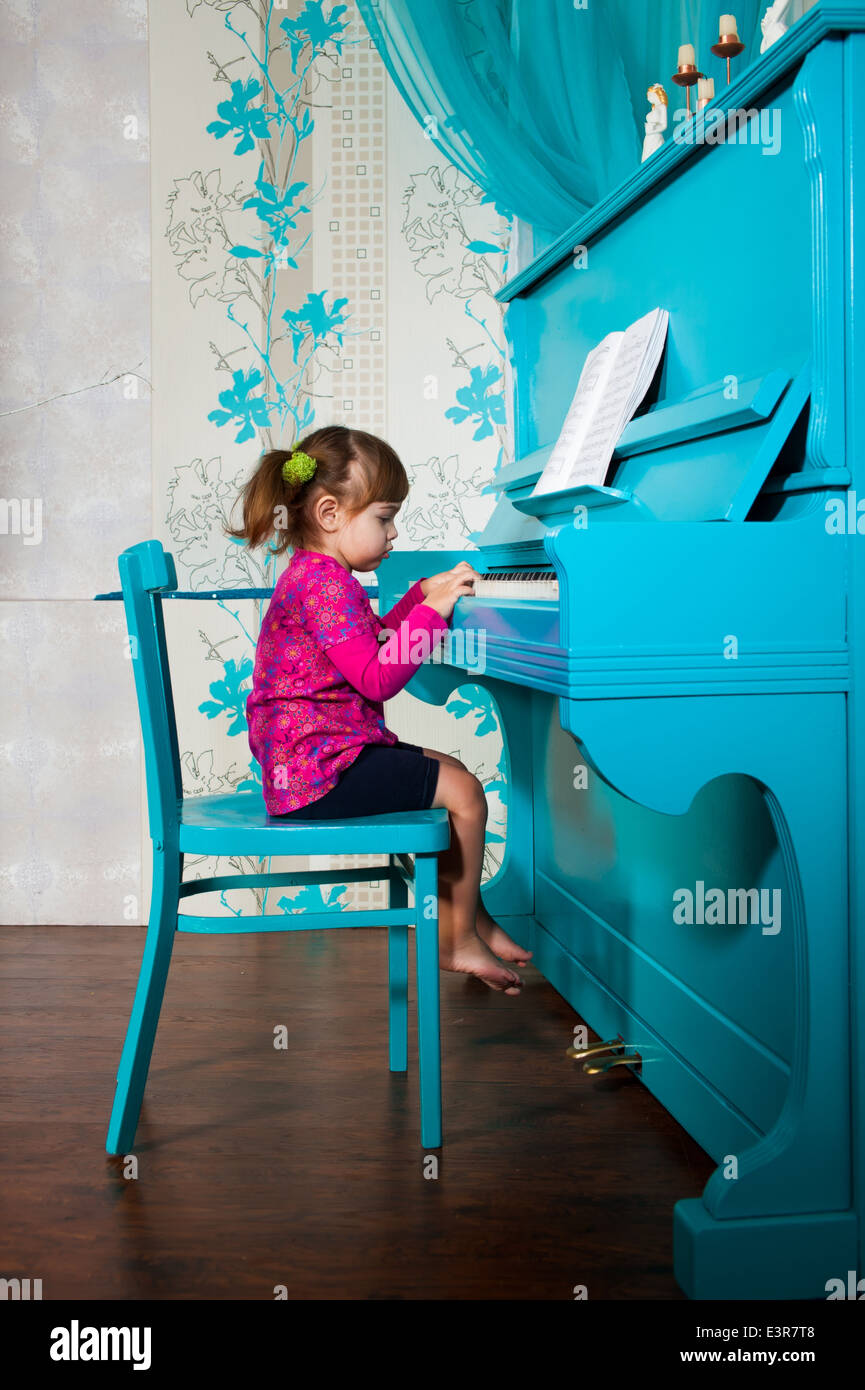 Kleines Mädchen spielt das blaue Klavier Stockfoto