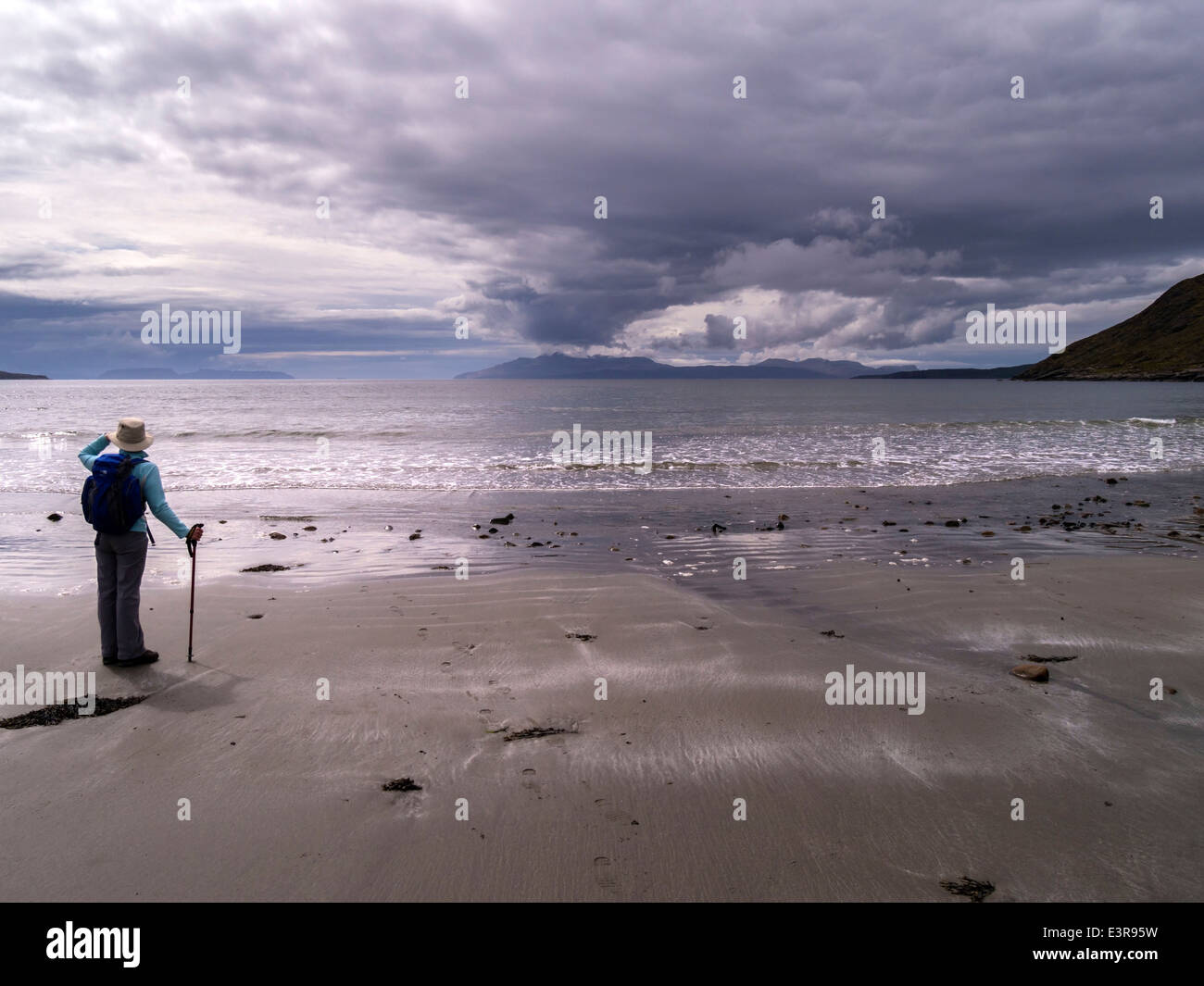 Einsamer Wanderer auf Camasunary Strand auf der Insel Skye, mit Blick über den Loch Scavaig auf die Insel Rum & Cloud Plume, Schottland, Großbritannien. Stockfoto