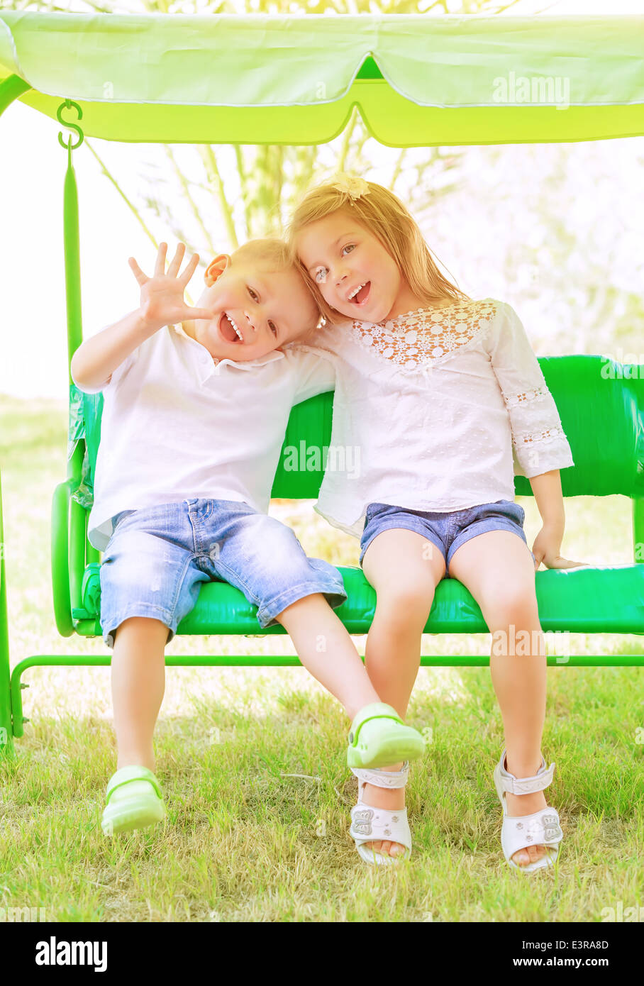 Niedlichen kleinen Bruder und Schwester, die Spaß auf der Schaukel im Hinterhof, fröhliche Kinder in Kindertagesstätten, Liebe und Freundschaft-Konzept Stockfoto