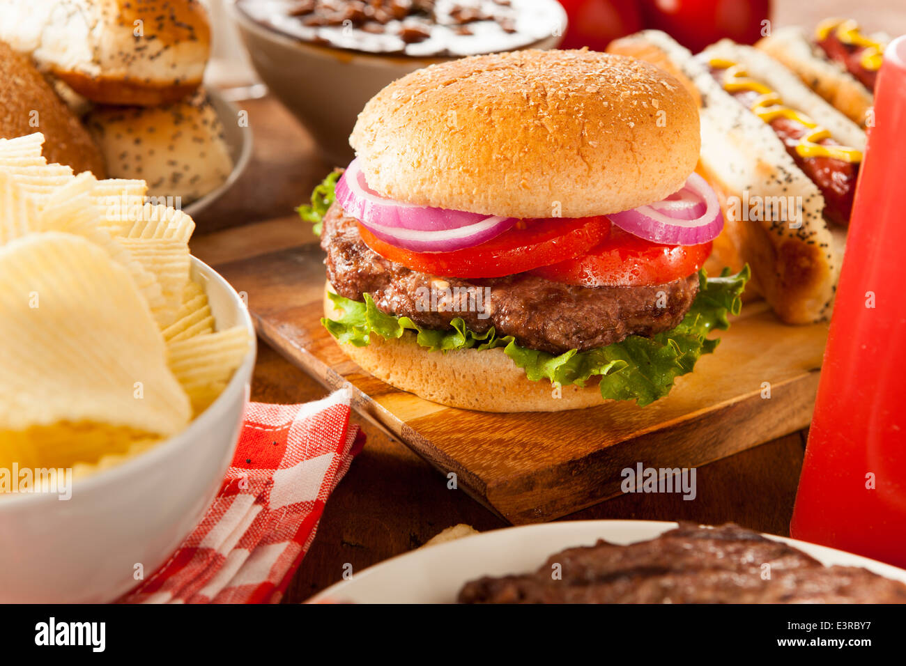 Herzhaftes vom Grill Hamburger mit Salat und Tomaten auf einem Brötchen Stockfoto