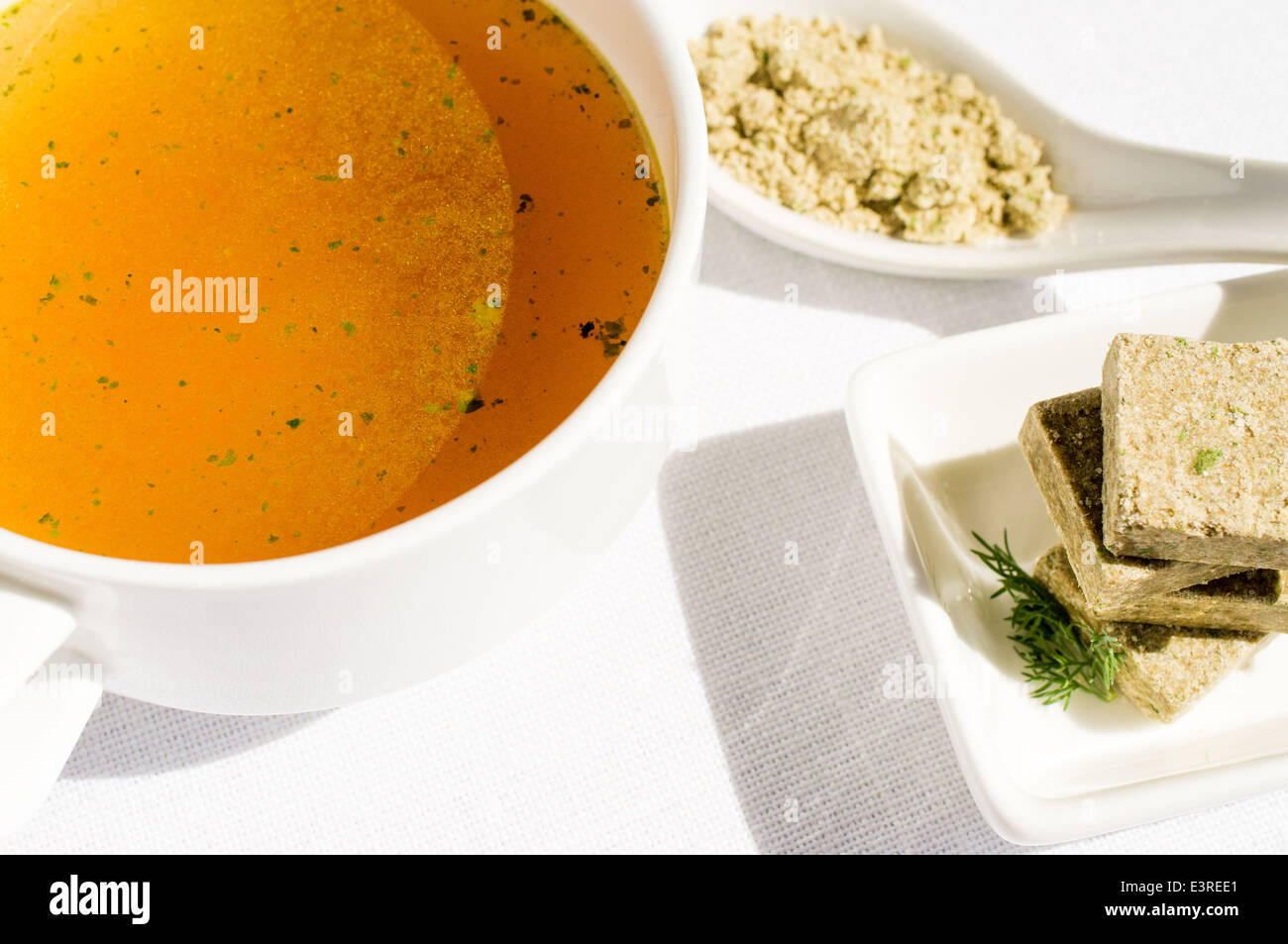 Konzentrierte Brühe, Bouillon, klare Suppe in eine Tasse und ein Brühwürfel Stockfoto