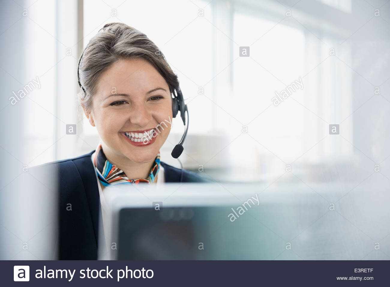 Flughafen-Kundendienstmitarbeiter mit Kopfhörer am computer Stockfoto
