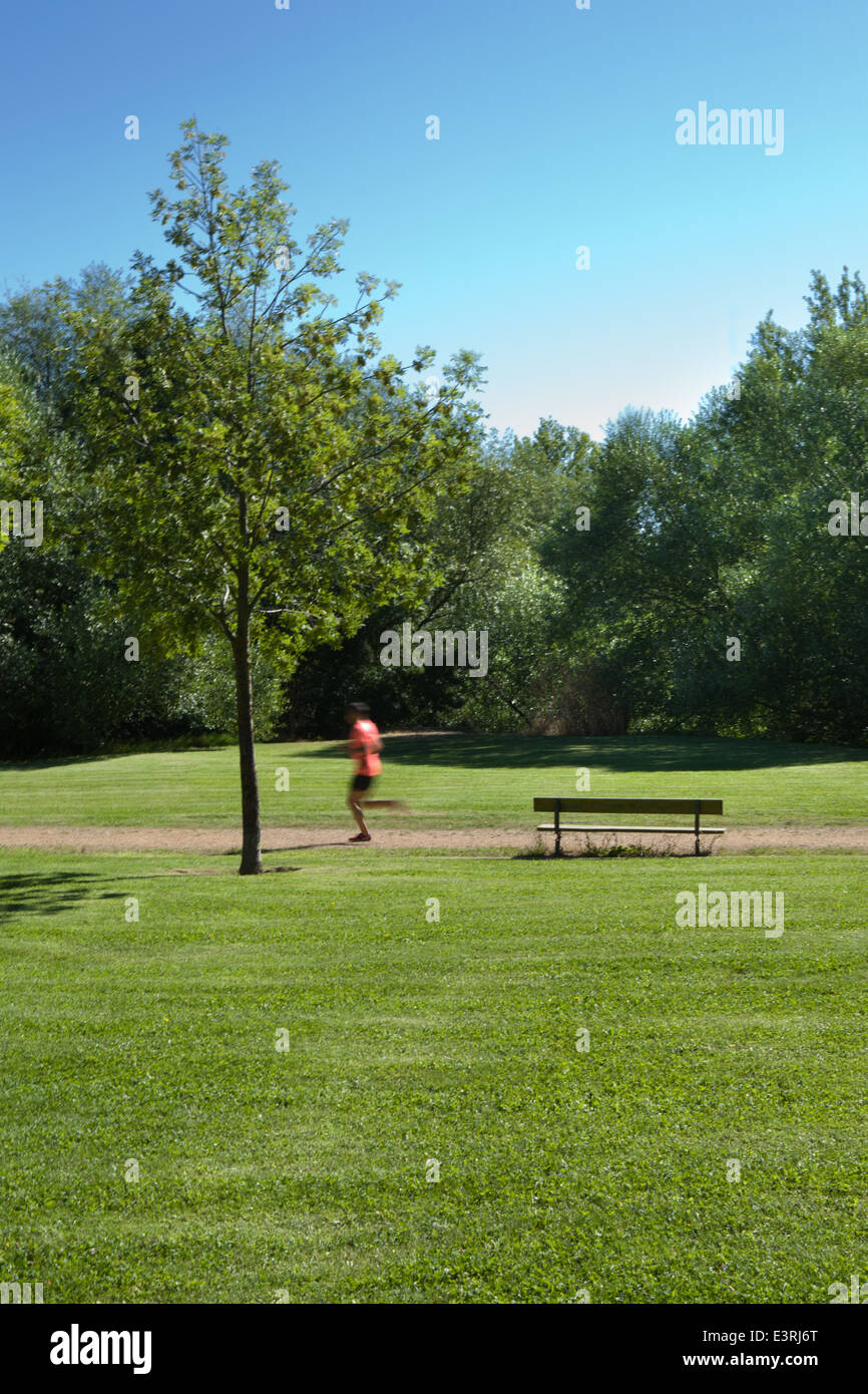 Mann läuft allein im Park zwischen einer Bank und einem Baum Stockfoto