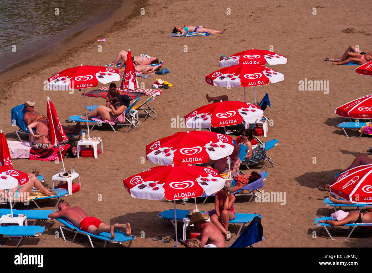 Menschen Sonnenbaden auf ein Sandstrand auf Sonnenliegen unter Sonnenschirmen Stockfoto