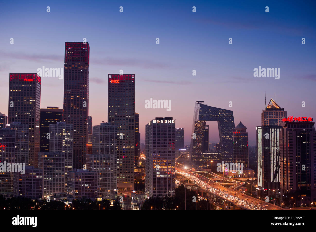 Schöner Blick auf die Skyline von Jianwai Soho und das berühmte Wahrzeichen des CCTV-Hauptquartiers, mit den Lichtern des Verkehrs auf der dritten Ringstraße und Büros und Gebäuden, die die Szene am frühen Abend erhellen. Seltene Panorama-Szene während der blauen Stunde kurz nach Sonnenuntergang mit klarem Himmel in Guomao, dem zentralen Geschäftsviertel der chinesischen Hauptstadt Peking, befindet sich im Chaoyang Bezirk, China, PRC. © Olli Geibel Stockfoto