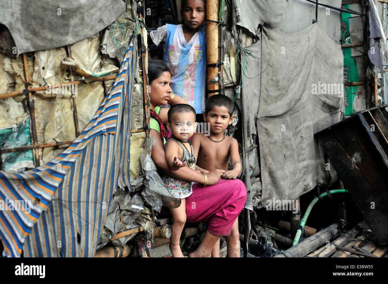 Dhaka, Bangladesch. 28. Juni 2014. Ein Bangladeshi Slum-Bewohner (L) beobachtet das zerstörte Haus, wie das Baby auf dem Arm die Hand nach einem großen Brand in Mirpur in Dhaka, Bangladesch, 28. Juni 2014 erreicht. Mindestens 450 Shanties im Feuer zerstört wurden, teilte die lokale Polizei. Bildnachweis: Shariful Islam/Xinhua/Alamy Live-Nachrichten Stockfoto