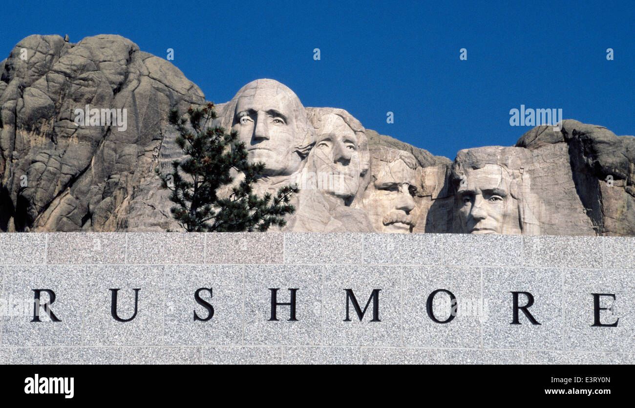 Die Gesichter der vier US-Präsidenten geschnitzt auf einen Berg Blick über ein Zeichen von Mount Rushmore National Memorial in den Black Hills von South Dakota, USA. Stockfoto