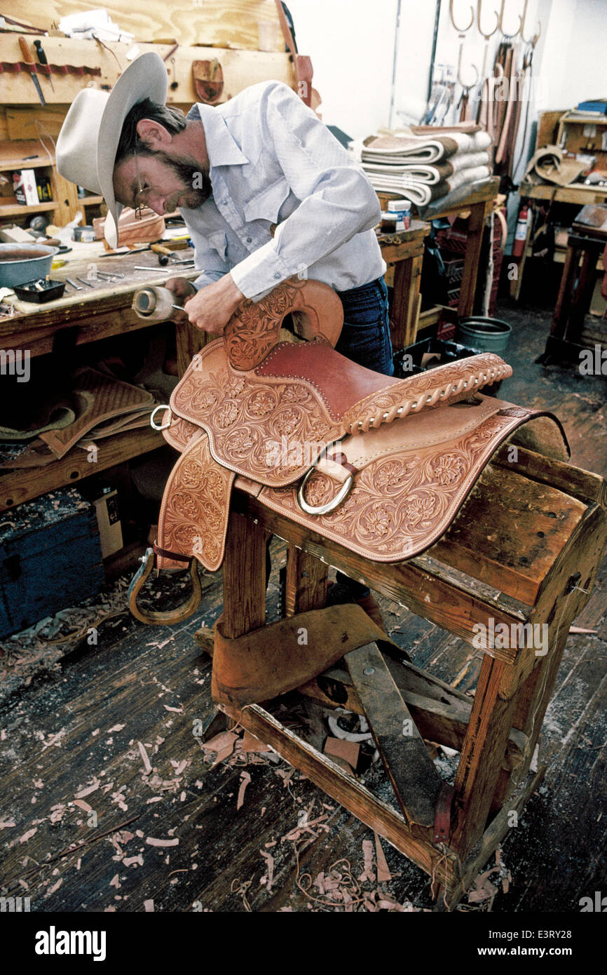 Eine Westernsattel Maker schnitzt Hand-fachmännisch kunstvollen Designs in das Leder ein neues schickes Pferd Sattel in seiner Werkstatt in Fort Worth, Texas, USA. Stockfoto