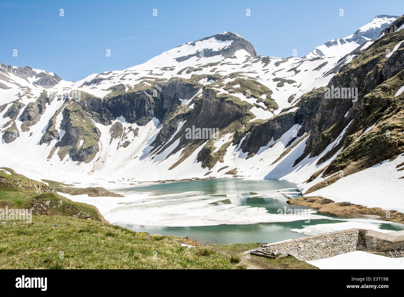 Schneeschmelze auf einem halb zugefrorenen See in den Alpen Stockfoto