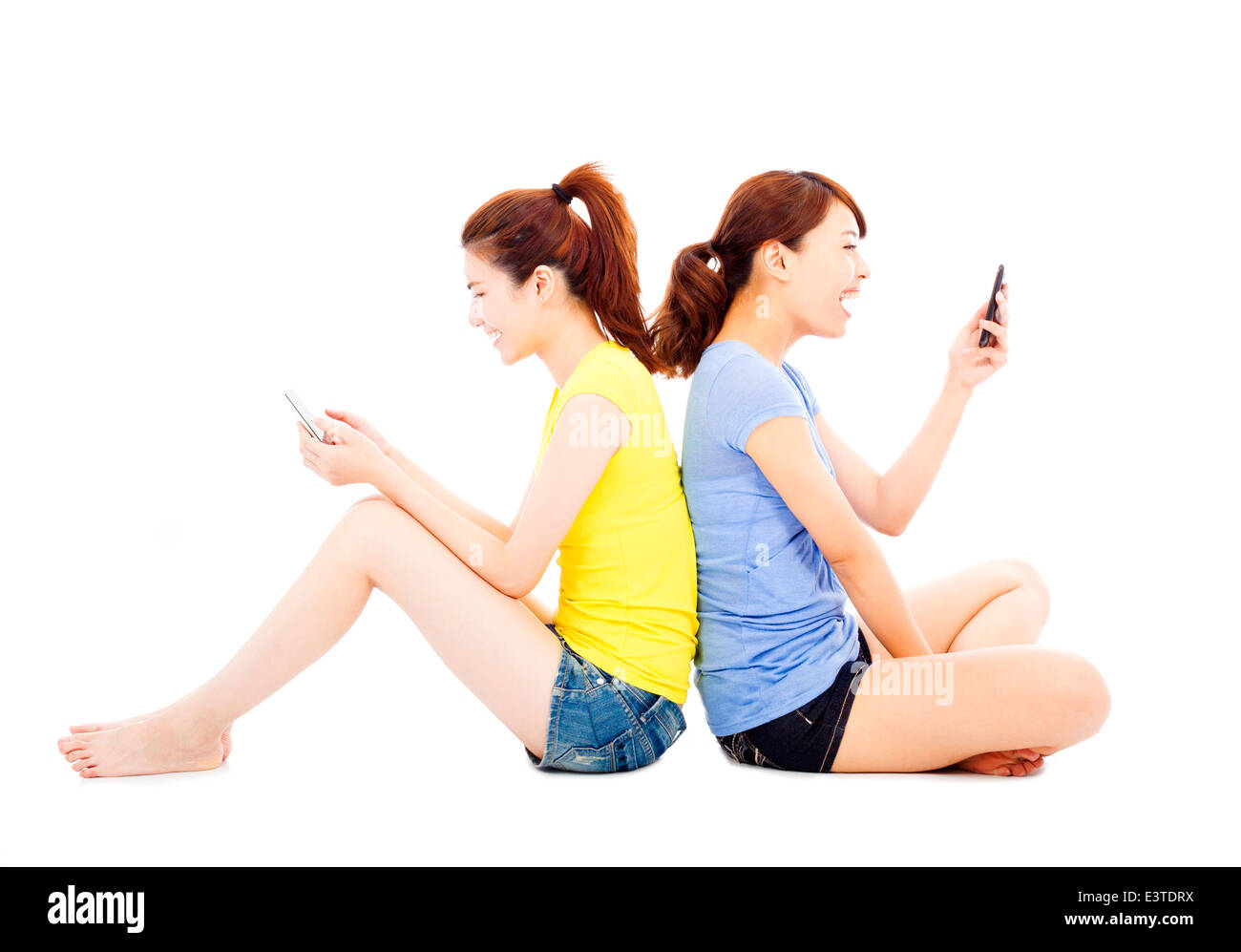 zwei glückliche hübsche Mädchen spielen Smartphone Stockfoto