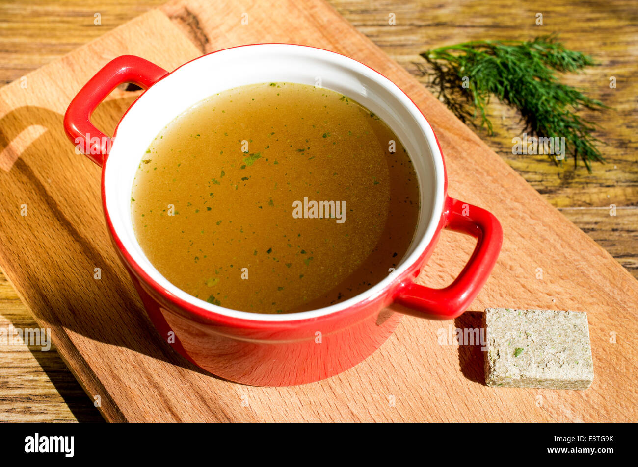 Konzentrierte Brühe, Bouillon, klare Suppe in eine Tasse und ein Brühwürfel Stockfoto