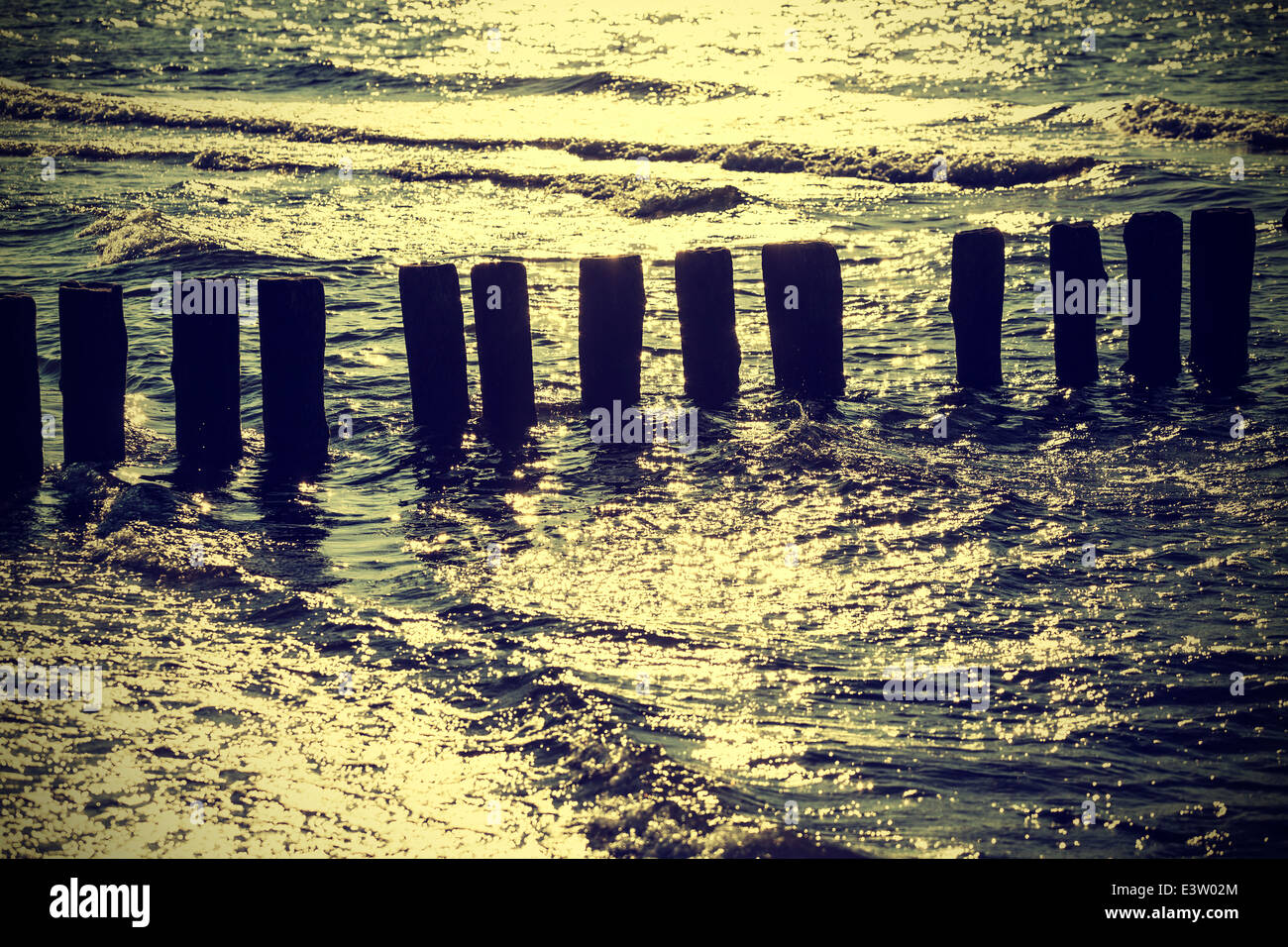 Hölzerne Pfähle im Wasser gegen Sonne, Vintage retro Instagram-Effekt. Stockfoto