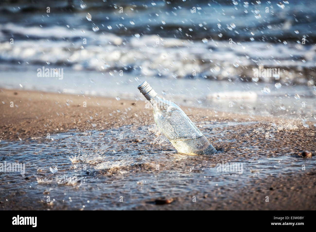Flasche mit Wasser Tropfen am Strand. Stockfoto