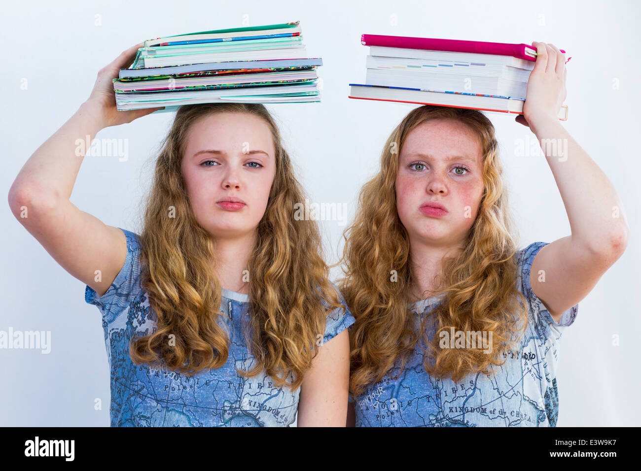 Zwei Schulmädchen mit Lehrbüchern über ihren Köpfen Stockfoto