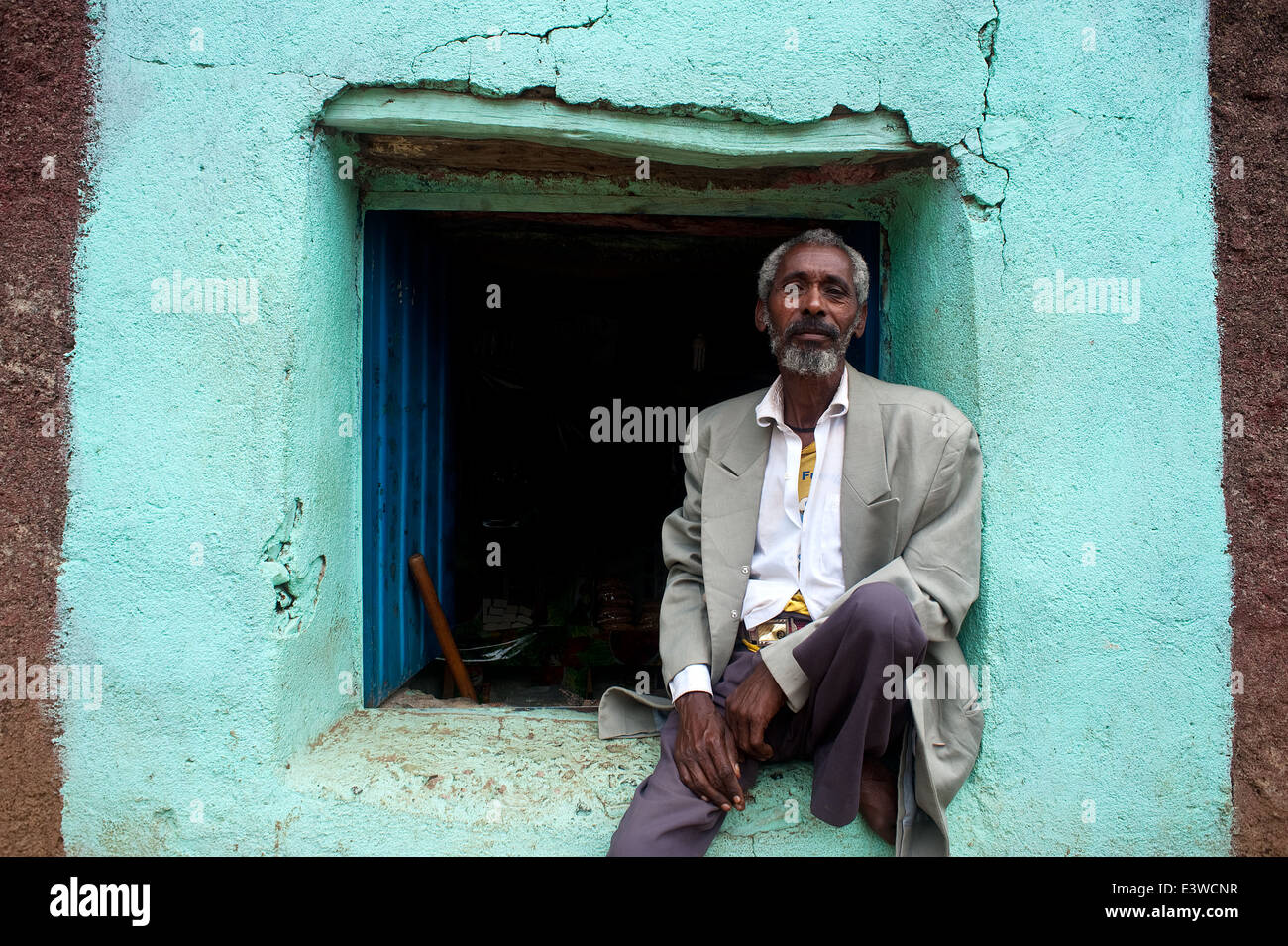 Mann sitzt auf dem Rand eines Fensters, die auf ein kleines Lebensmittelgeschäft (Äthiopien) Stockfoto