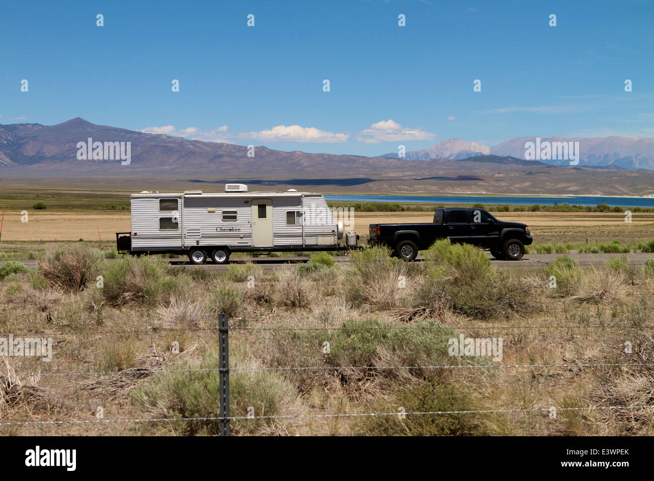 Lkw Ziehen eines Anhängers entlang einer Bergstraße (hwy 395) mit einem See im Hintergrund. Die Berge der Sierra Nevada, Kalifornien USA Stockfoto