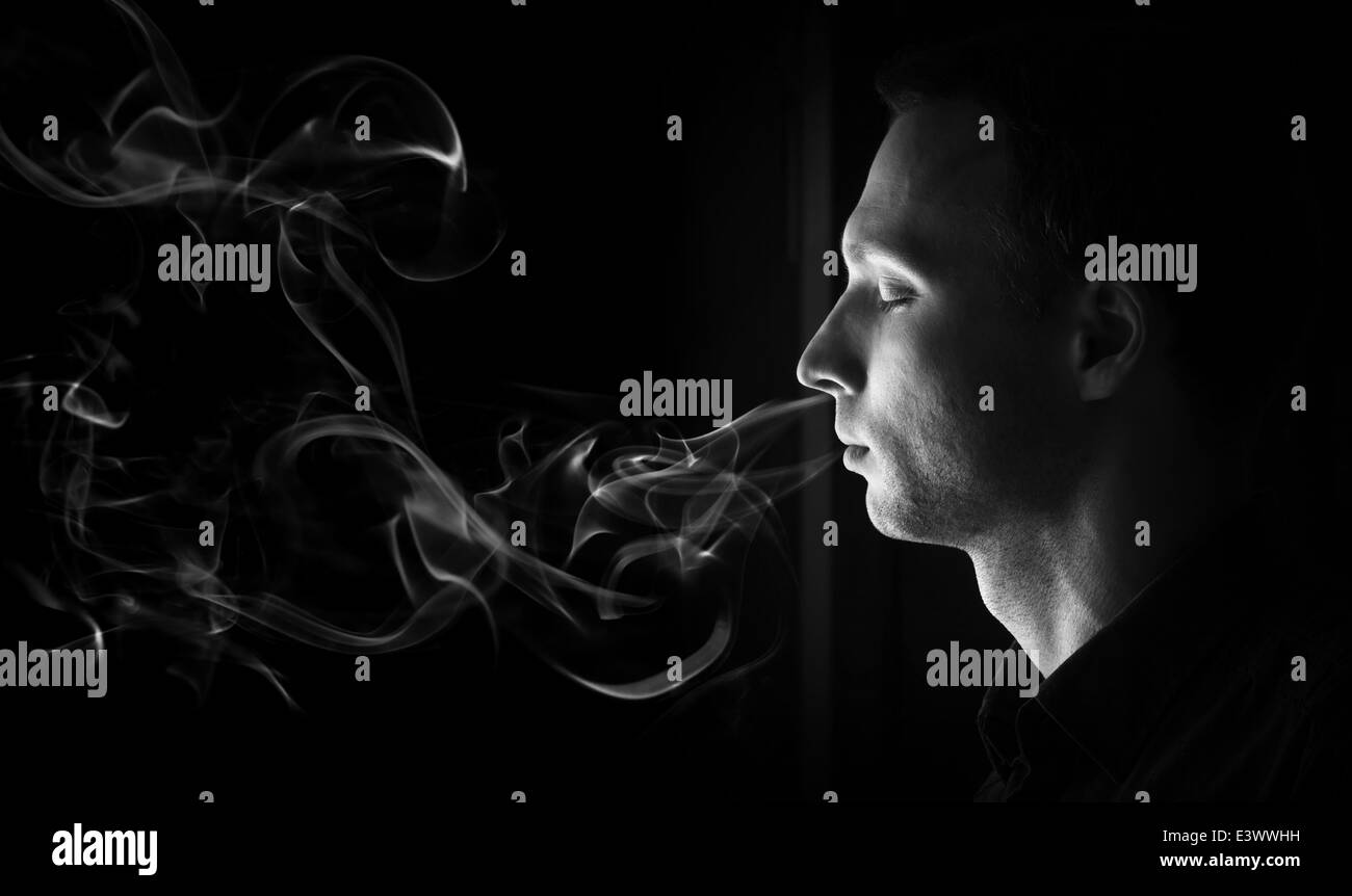 Closeup Profilbildnis des jungen Mannes mit geschlossenen Augen und Rauch Stockfoto