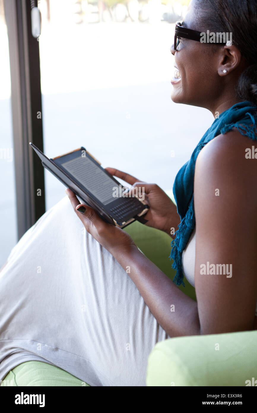 Ethnische Frau lachend in Coffee-Shop ein elektronisches Lesegerät lesen. Stockfoto