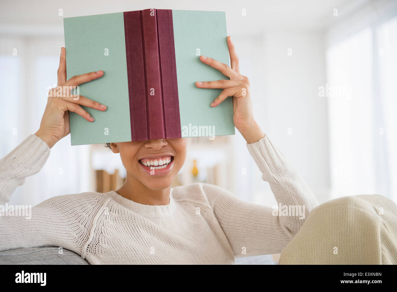 Schwarze Frau versteckt sich hinter Buch Stockfoto