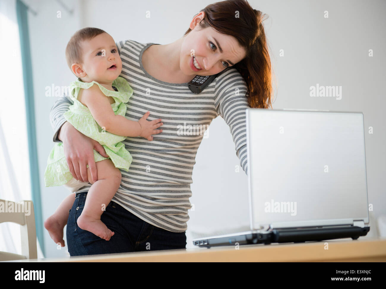 Mutter Multitasking mit baby Stockfoto