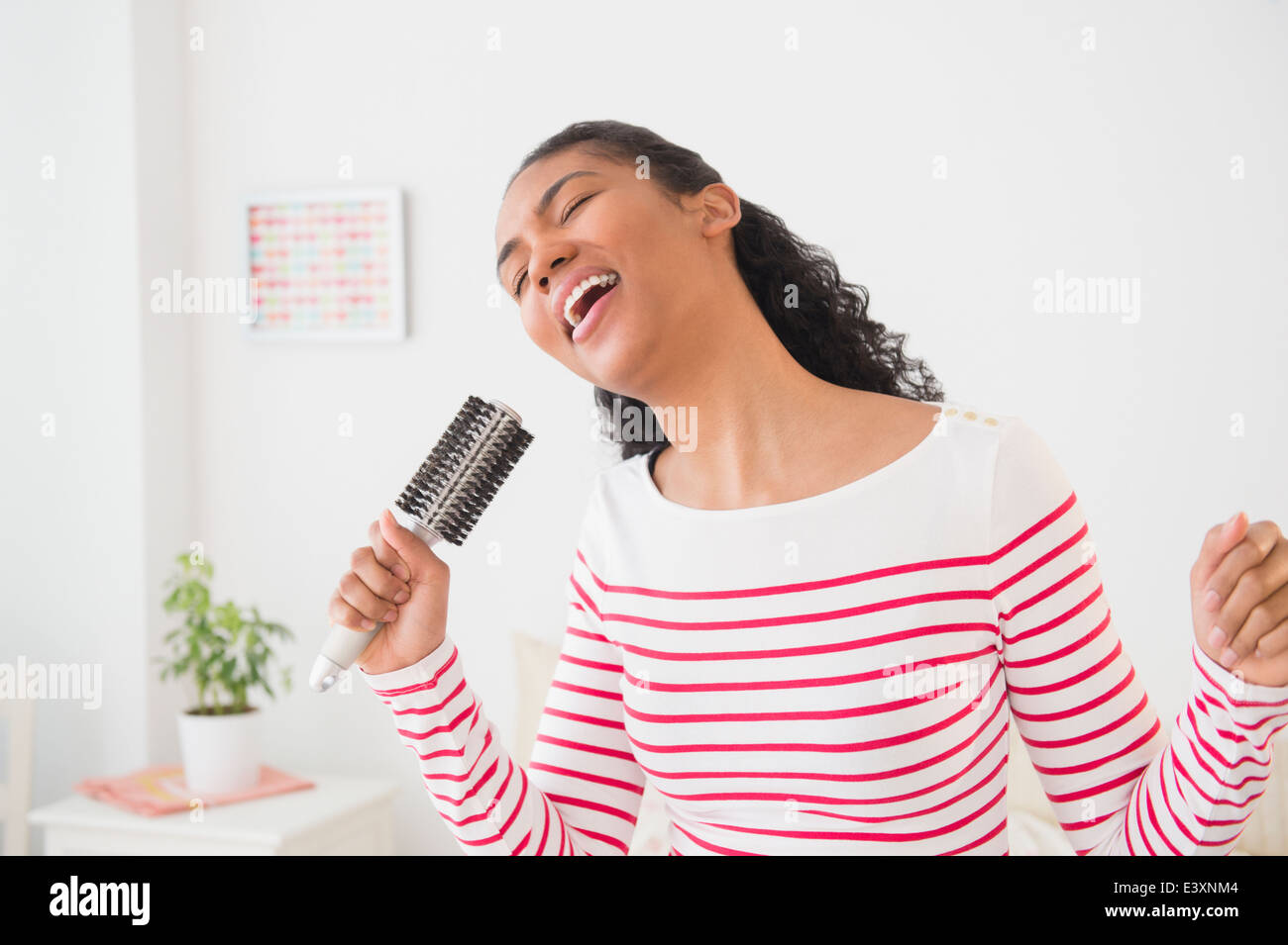 Gemischte Rassen Frau singt in der Haarbürste Stockfoto