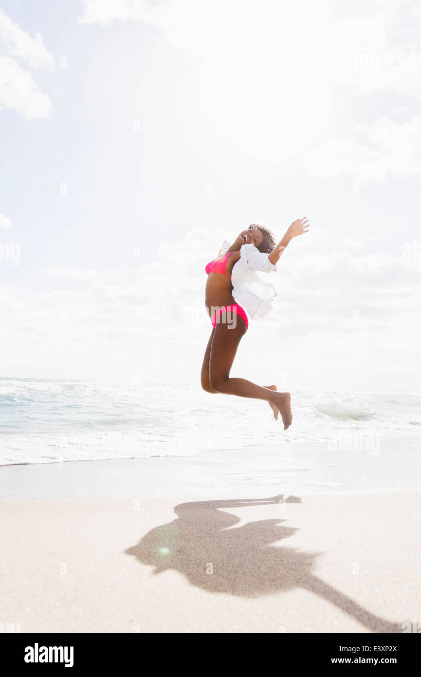 Afroamerikanische Frau springen vor Freude am Strand Stockfoto