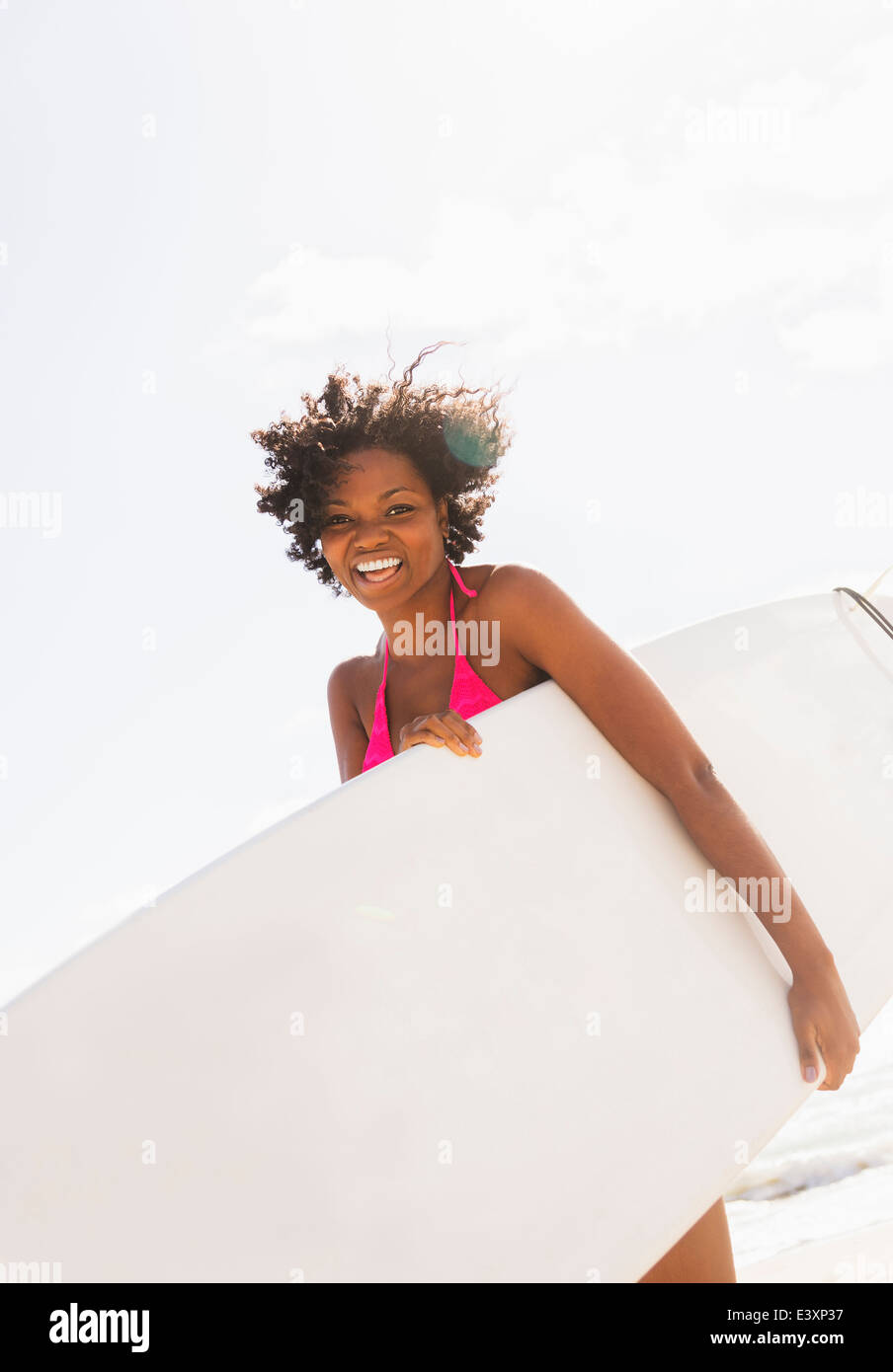 Afroamerikanische Frau mit Surfbrett am Strand Stockfoto