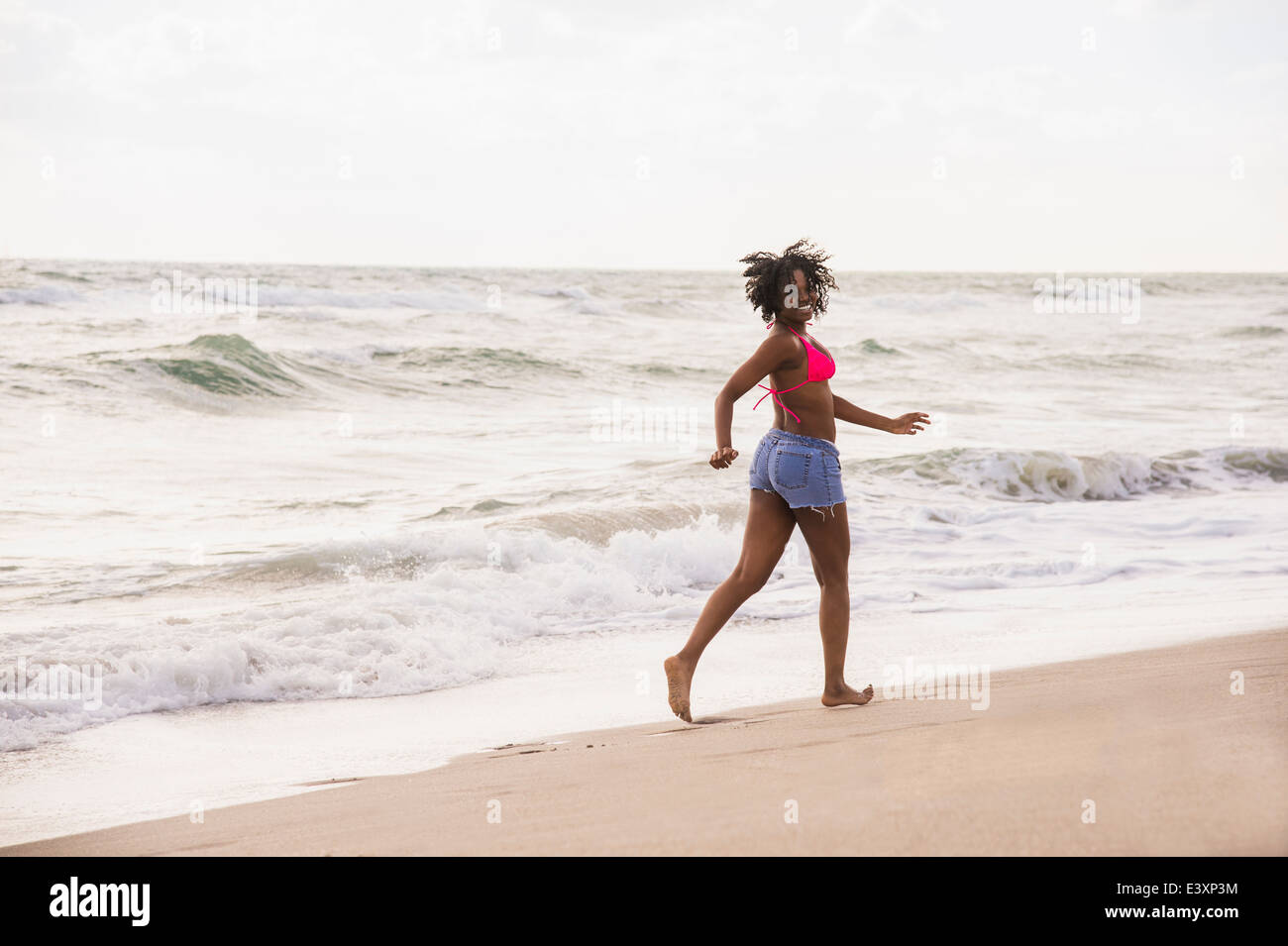 Afrikanische amerikanische Frau zu Fuß am Strand Stockfoto