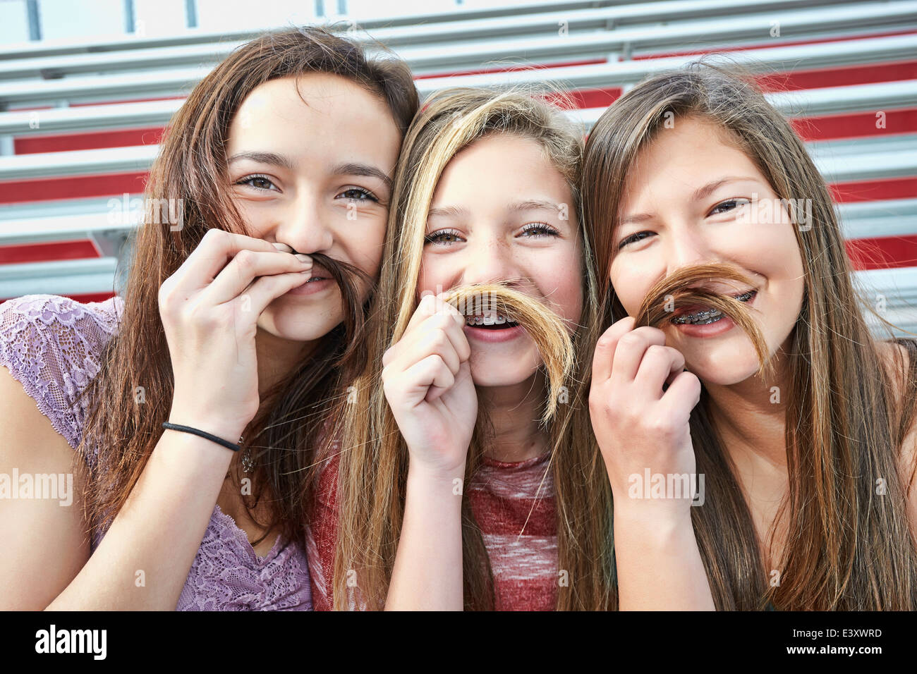 Mädchen im Teenageralter machen falsche Schnurrbärte mit Haaren Stockfoto