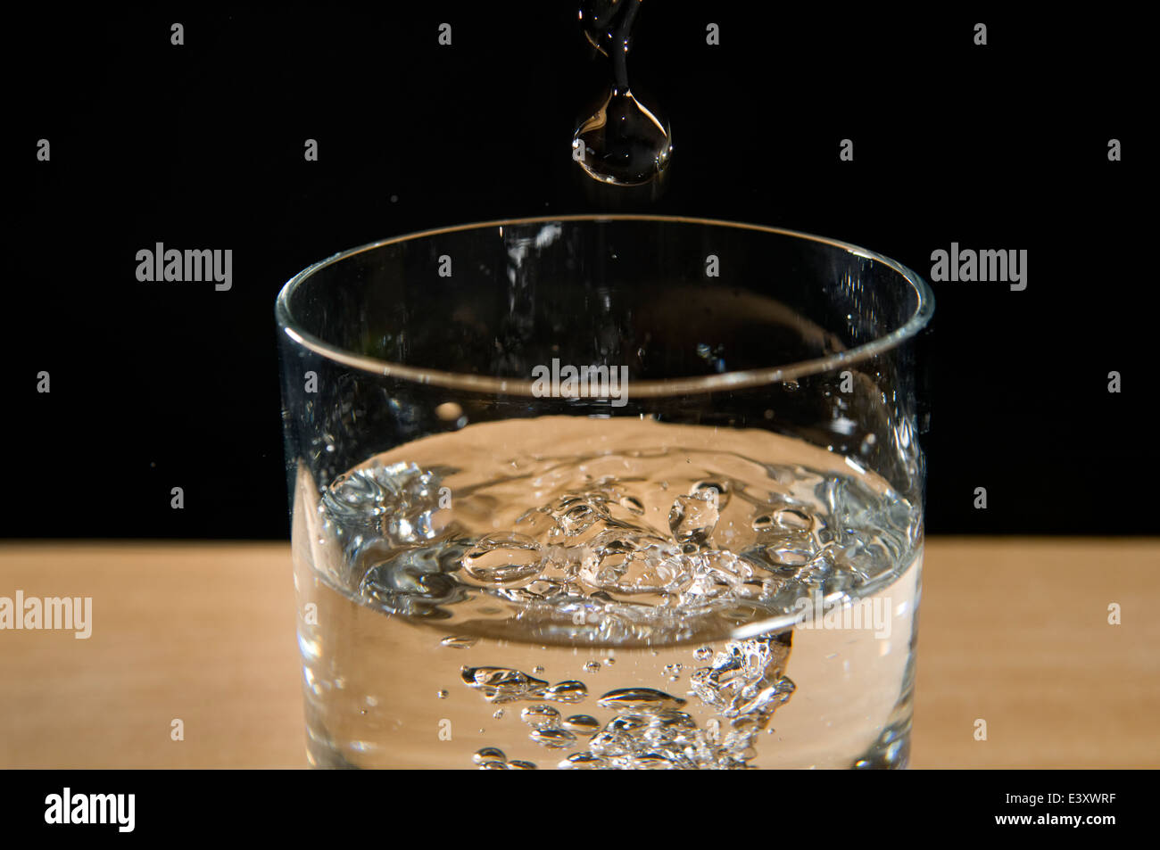 Wassertropfen im Glas mit frischem Wasser auf schwarzem Hintergrund Stockfoto