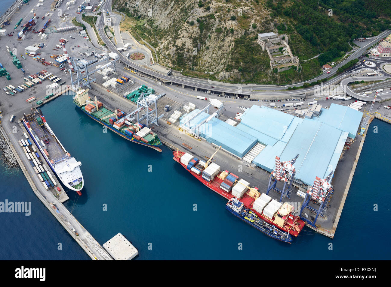 LUFTAUFNAHME. Containerschiffe entlang der Ladedocks im Handelshafen von Savona. Begggi, Provinz Savona, Ligurien, Italien. Stockfoto