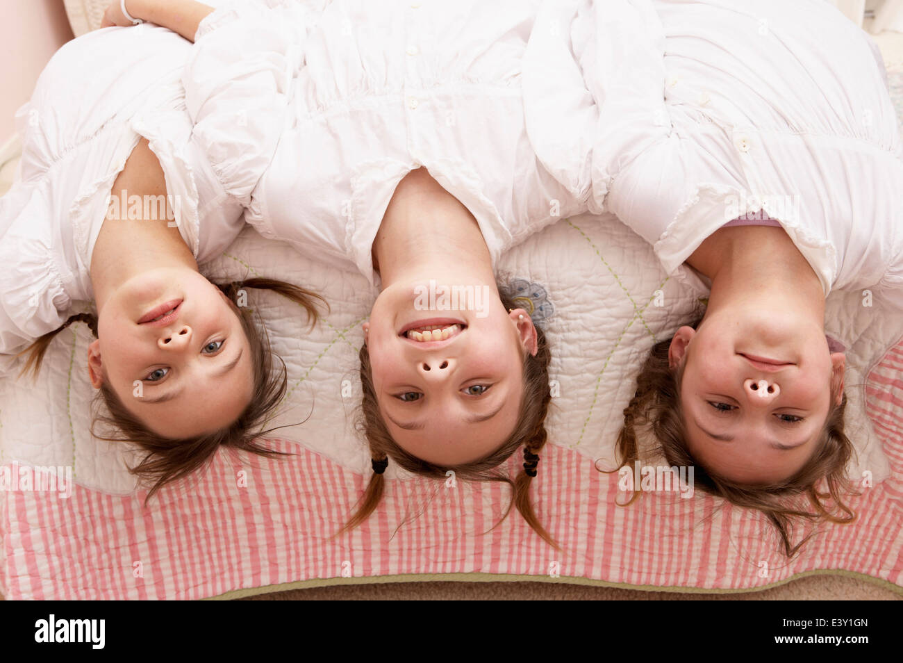 Gemischte Rassen Mädchen kopfüber aus dem Bett Stockfoto