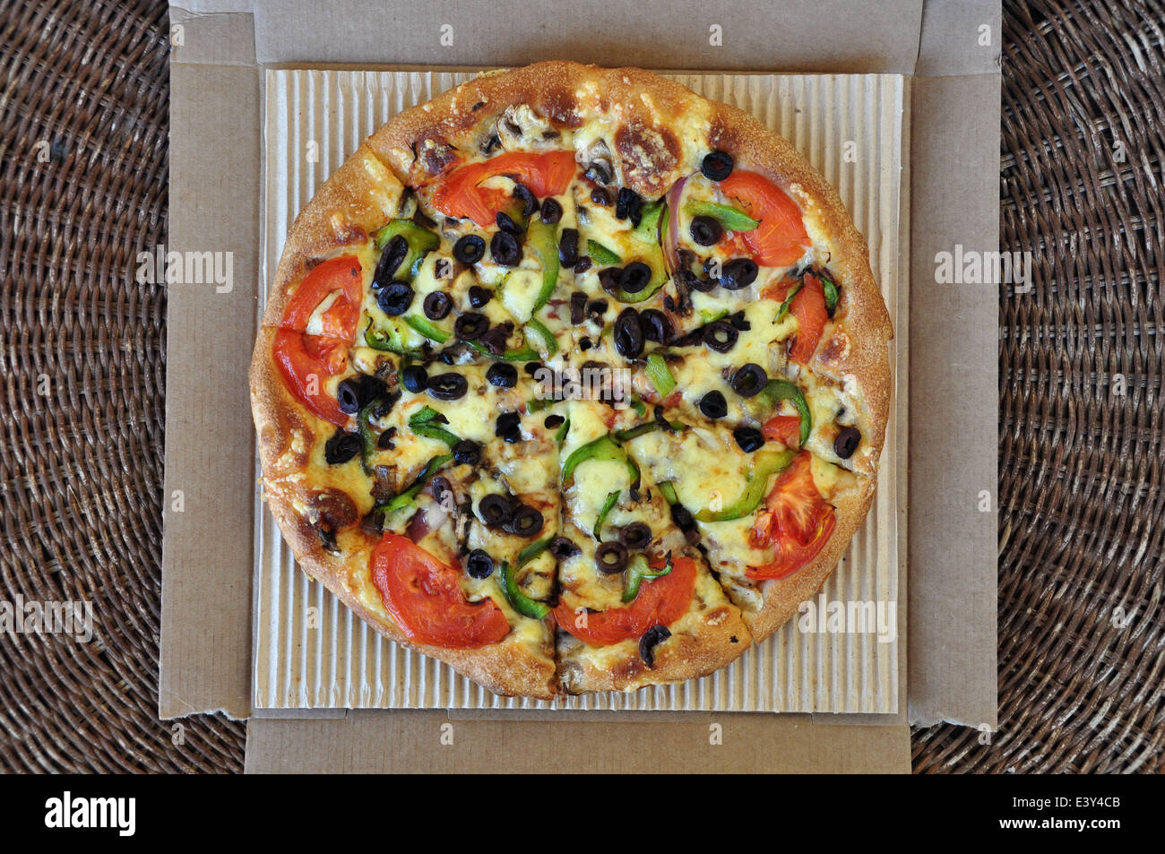 Vegetarische Pizza mit Tomaten, Oliven, Paprika, Champignons und Zwiebeln in Karton verpackt. Hintergrund der italienischen Speisen zum mitnehmen. Stockfoto