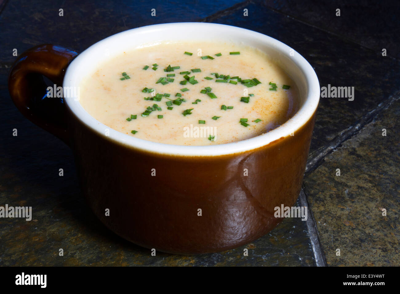 Topf der Bier-Käse-Suppe auf Schiefer Tisch mit Schnittlauch Stockfoto