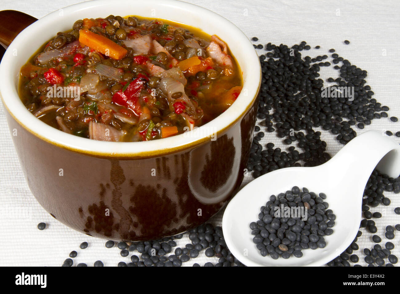 Crock mit herzhaften Suppe mit Belugalinsen, Karotten, Paprika und Schinken Stockfoto