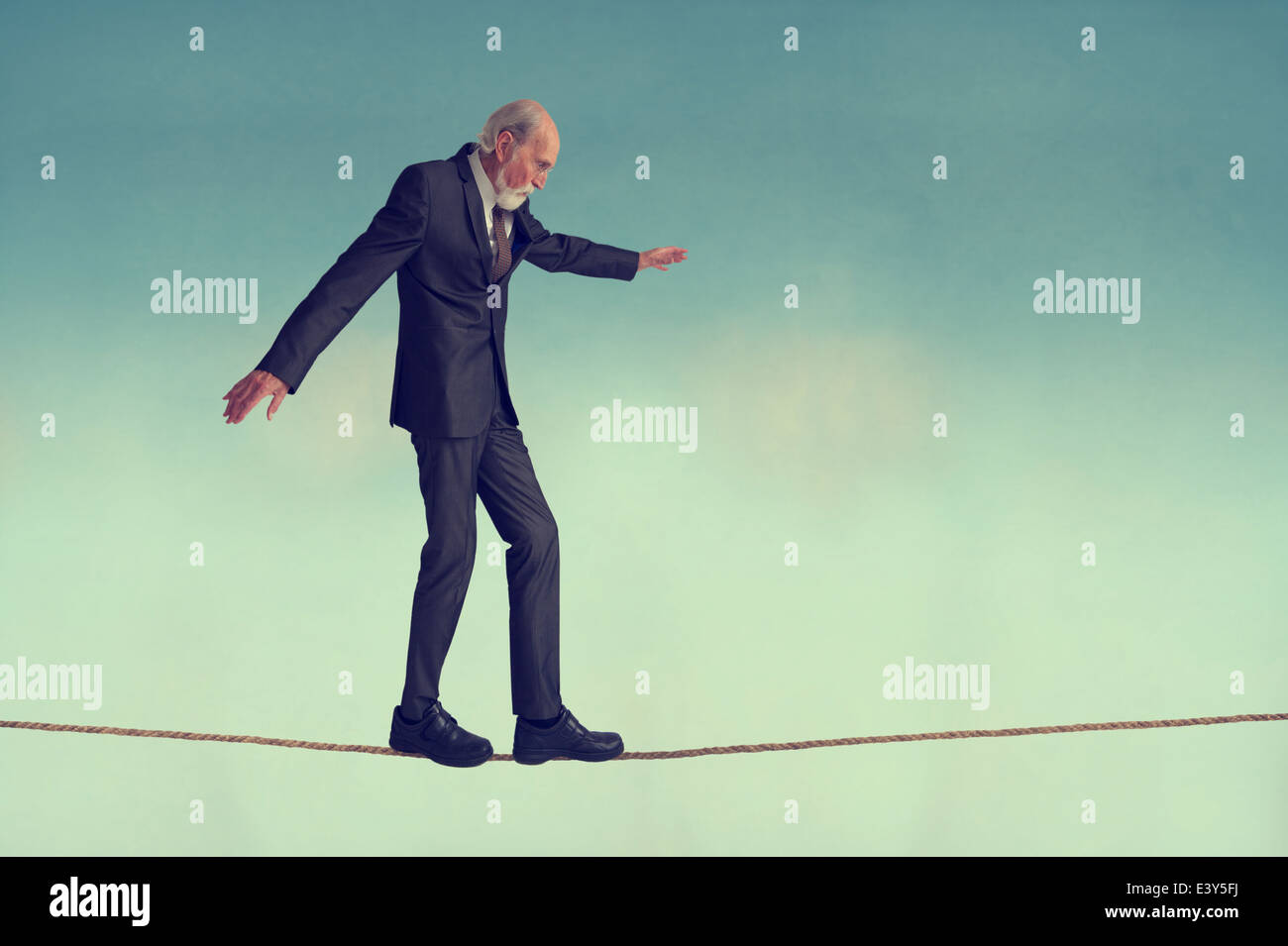 ältere Mann zu Fuß auf einem Drahtseil oder Highwire sorgfältig balancieren Stockfoto
