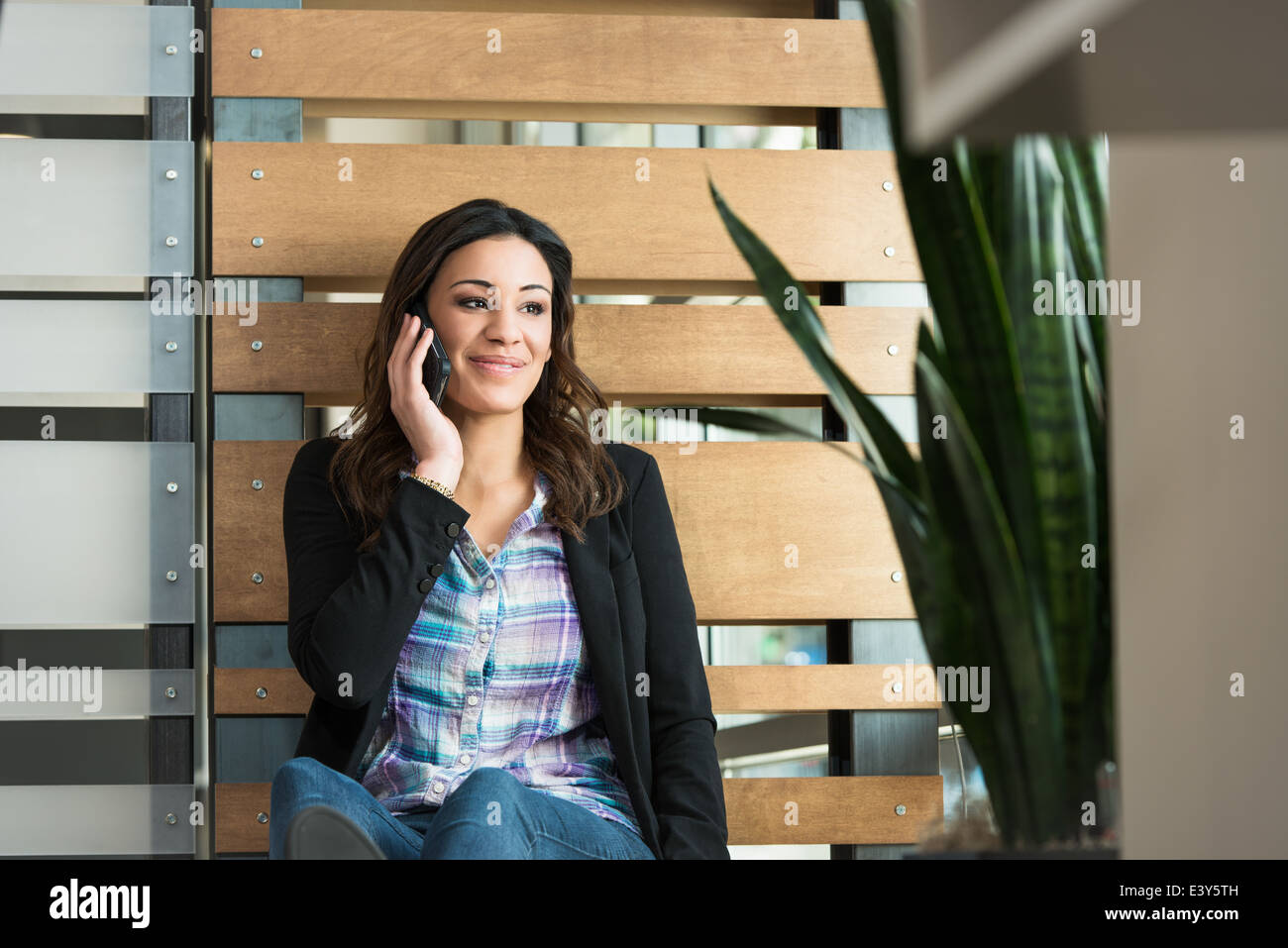 Junge weibliche Büroangestellte im Chat auf Smartphone im Büro Stockfoto