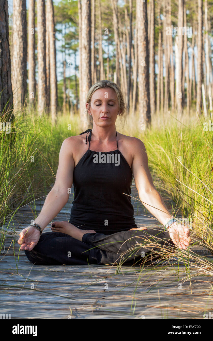 Reife Frau praktizieren Yoga Meditation über Wald Gehweg Stockfoto