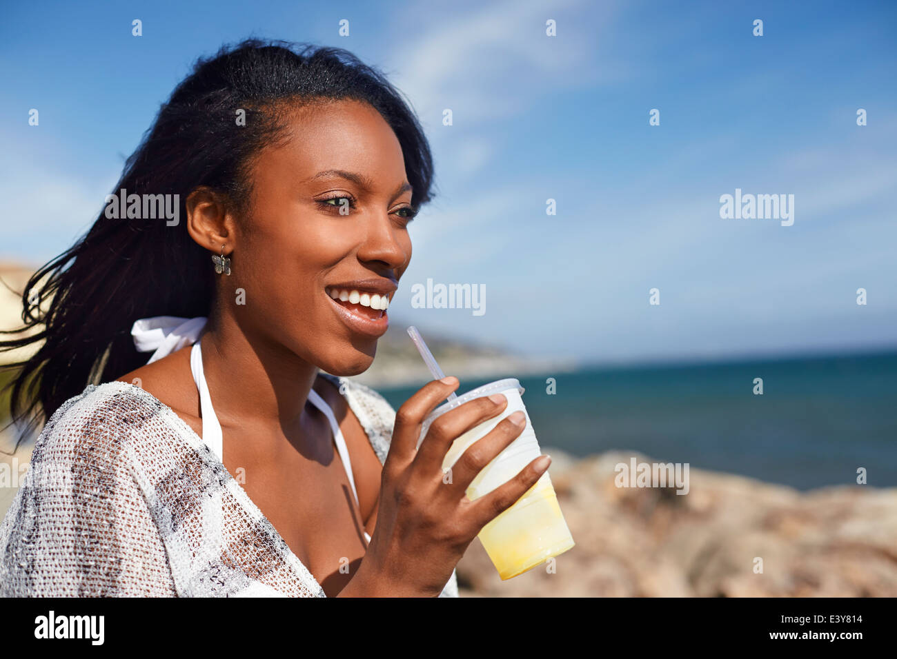 Junge Frau trinkt Fruchtsaft am Strand, Malibu, Kalifornien, USA Stockfoto