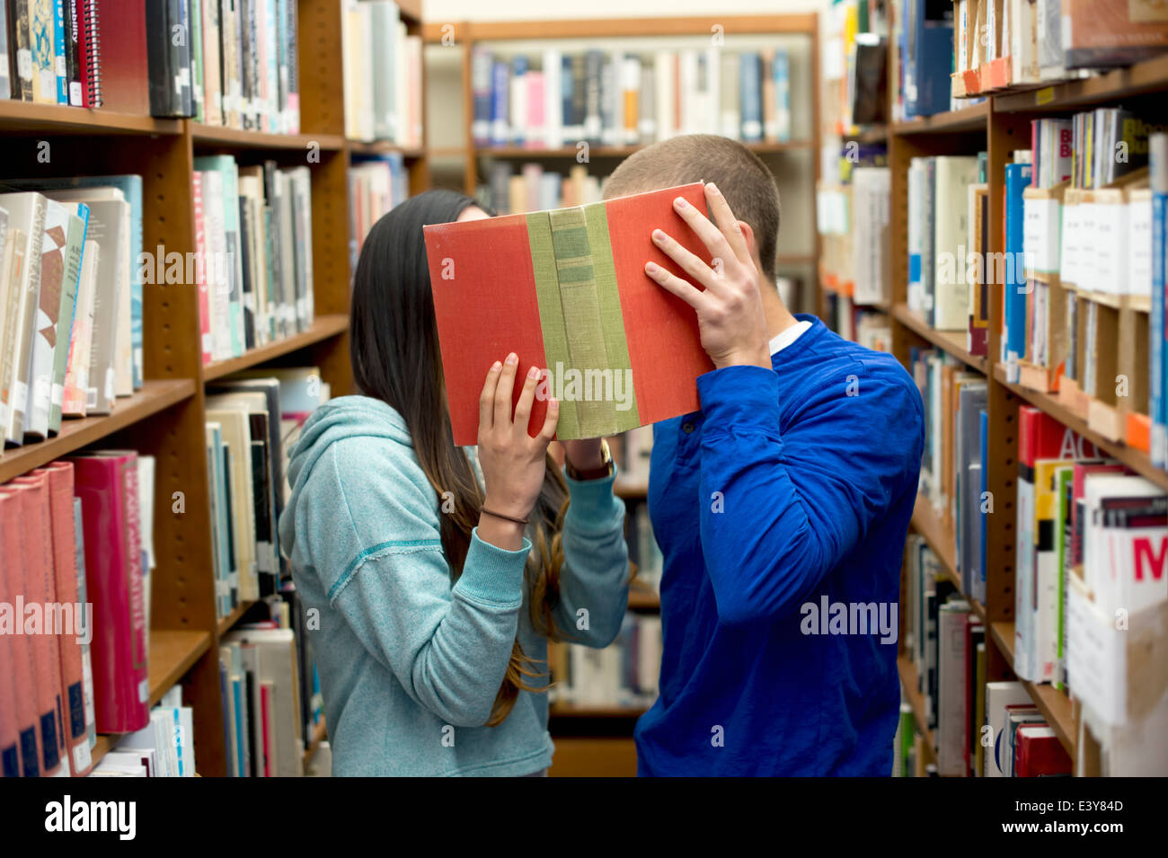 Junges Paar versteckt sich hinter Buch Stockfoto