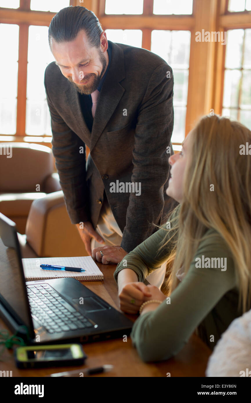 Junge Frau mit Laptop im Gespräch mit Lehrer Stockfoto