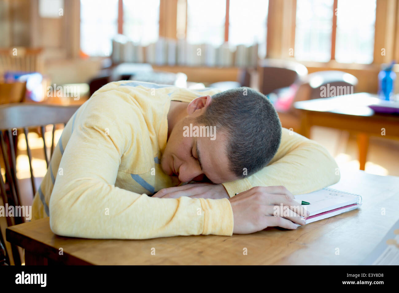 Junger Mann schlafend auf Buch Stockfoto