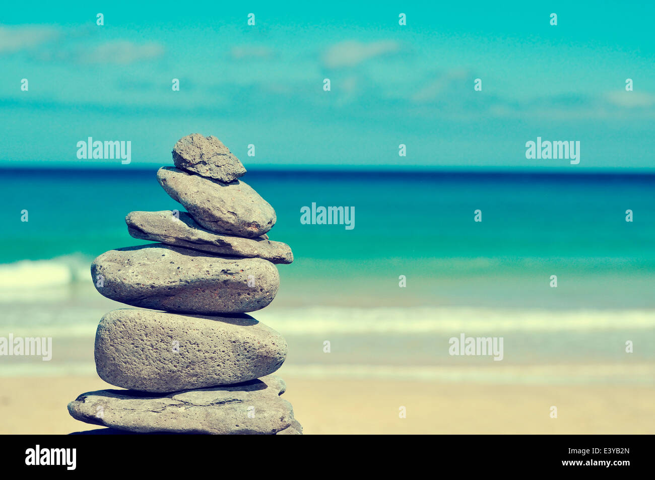 Stapel von ausgewogenen Steinen in einem weißen Sandstrand mit Crossen-Effekt Stockfoto