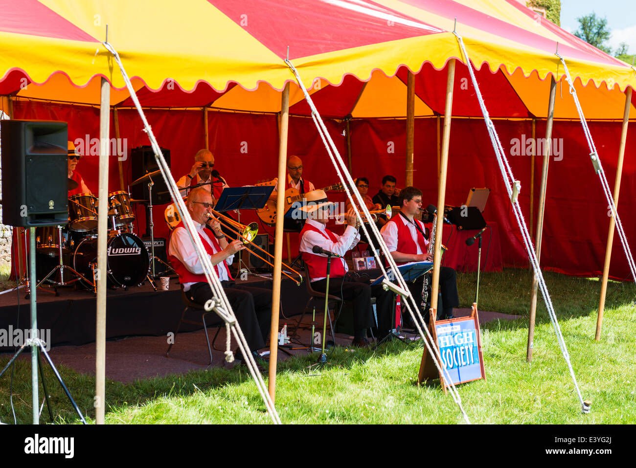 East Devon, England. Die Trad Jazz Band High Society spielen traditionellen Jazz auf einer Fete und Gartenfest unter einem Zelt im Sommer. Stockfoto