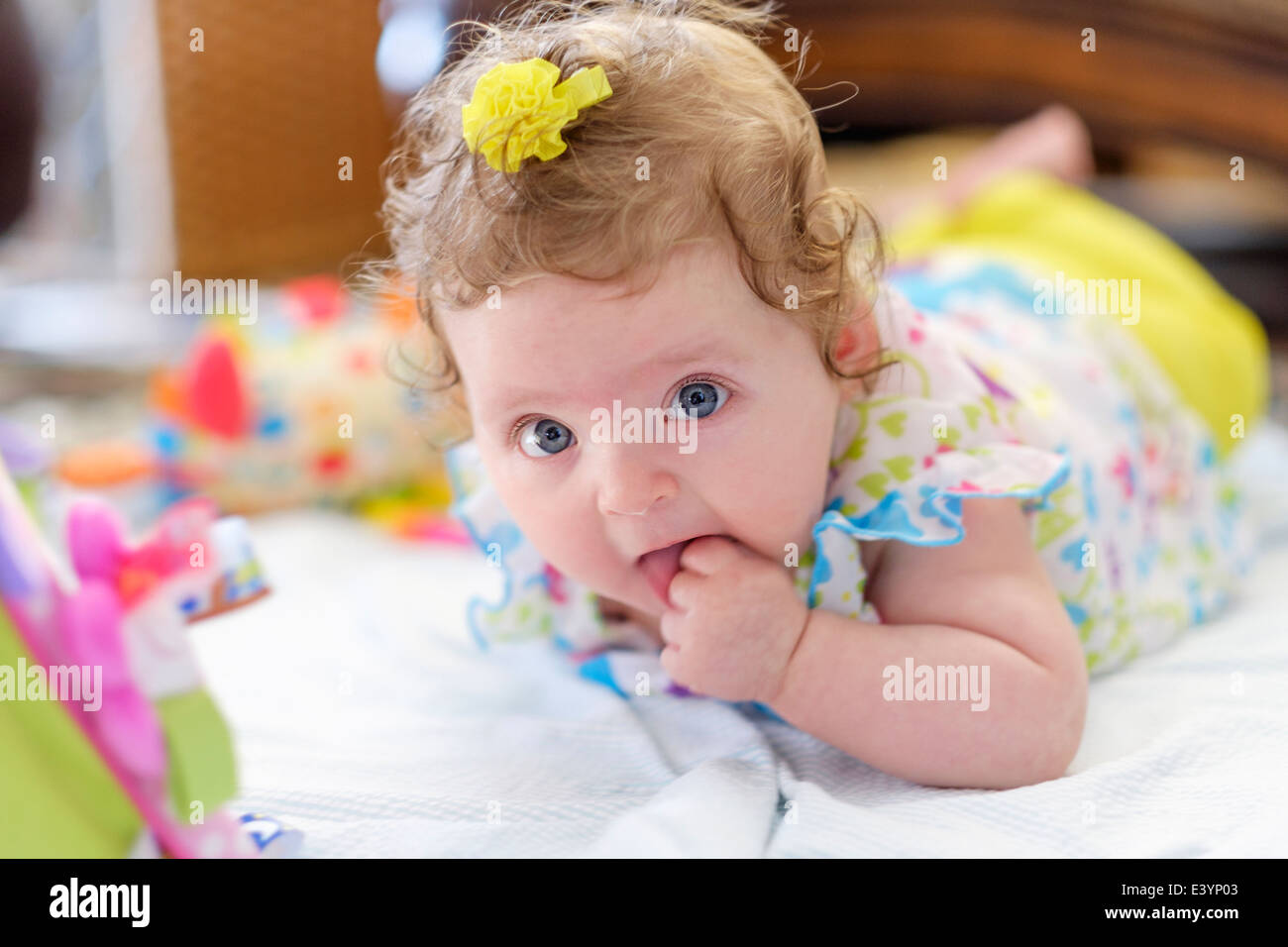 Ein drei Monate altes kaukasischen Kleinkind Mädchen, liegend auf Bauch kauen auf Faust. Stockfoto