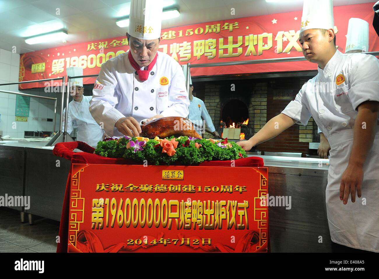 Peking, China. 2. Juli 2014. Chefkoch Zheng Zhiqiang Orte Quanjude 196 millionste gebratene Ente auf einem Teller im Rahmen einer Feierstunde zum 150. Jubiläum der Quanjude Peking Roast Duck Restaurant in seiner Qianmen-Niederlassung in Peking, Hauptstadt von China, 2. Juli 2014. Quanjude, das für seine langjährige kulinarische Heritge seit seiner Gründung im Jahre 1864 in seiner Qianmen-Niederlassung in Peking bekannt ist, erhielt ihr 150-jähriges bestehen und eine Zeremonie anlässlich seiner 196 Millonth gebratene Ente war auch hier statt. Bildnachweis: Zhang Yan/Xinhua/Alamy Live-Nachrichten Stockfoto