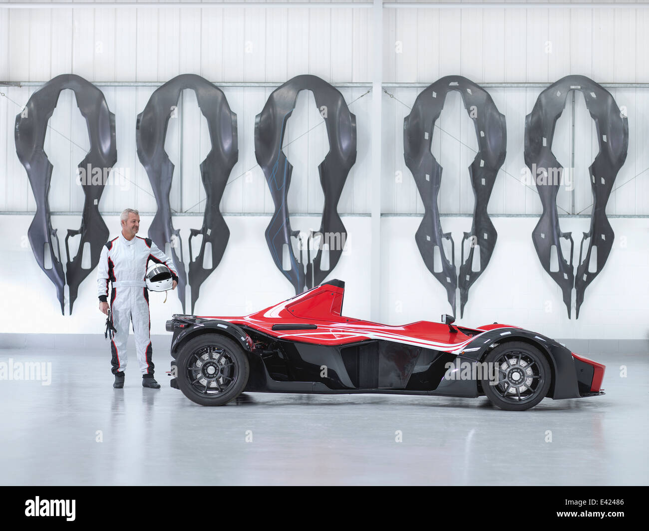 Rennfahrer mit Supersportwagen in Fabrik mit Carbon Fibre Auto Karosserien an Wand Stockfoto