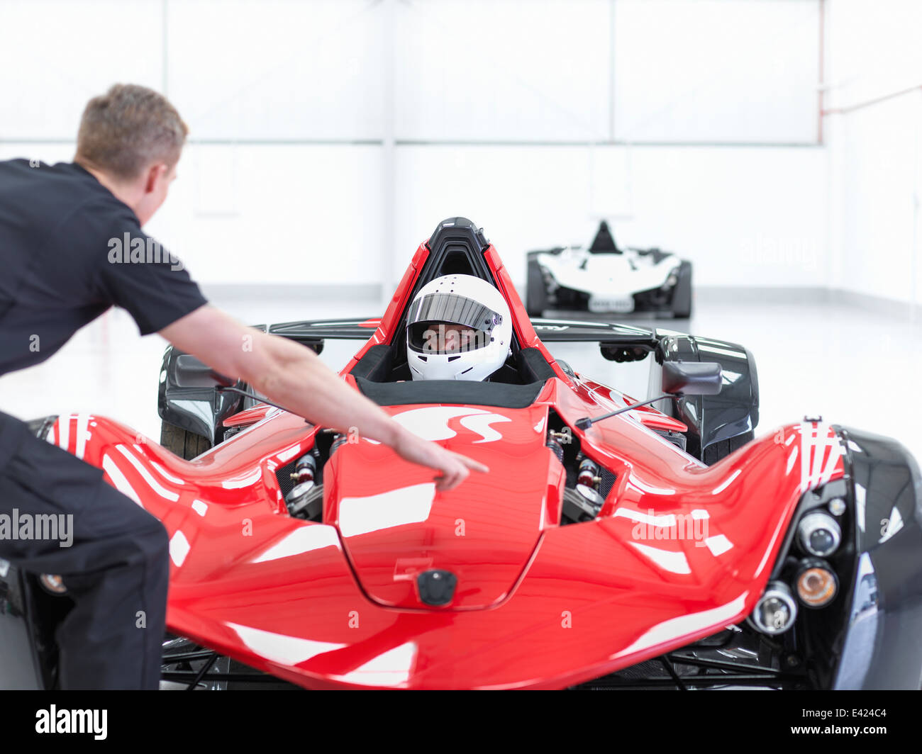 Ingenieur und Rennfahrer in Supersportwagen im Sportwagen-Fabrik Stockfoto