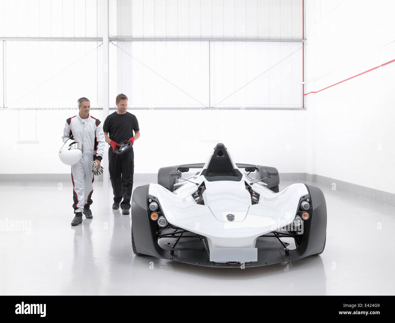 Rennfahrer mit dem Ingenieur und Supersportwagen im Automobilwerk Stockfoto